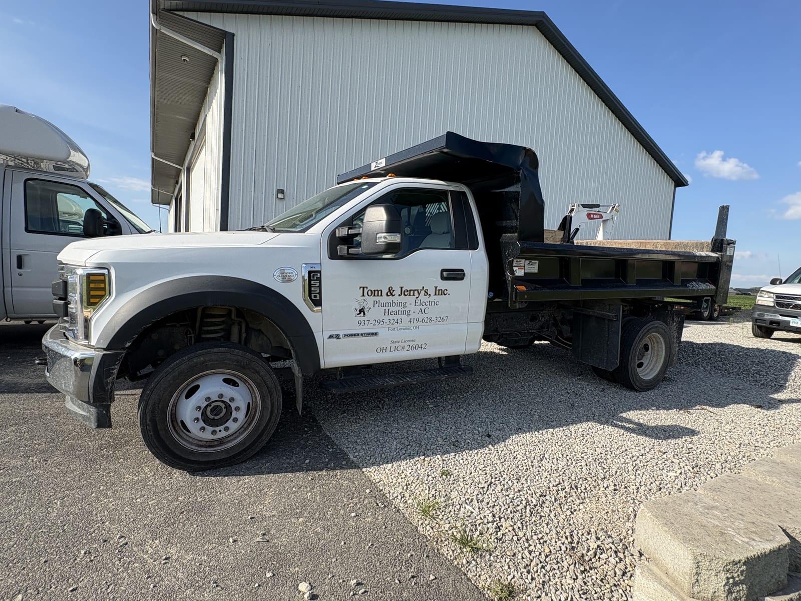 Tom & Jerry's dump truck loaded with a skid steer, parked at the Fort Loramie shop
