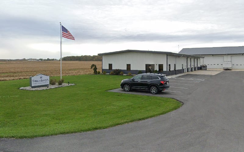 The Tom & Jerry's shop and yard on Dawson Road in Fort Loramie, flag flying and the road sign out front