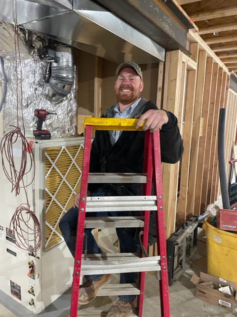 A Tom & Jerry's technician at a furnace and filter housing on a service call